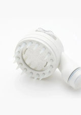 A white electric facial cleansing brush head with multiple silicone bristles and a clear plastic cover, shown on a clean white background.