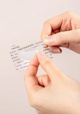 Hands peeling off a clear label with text from a surface.