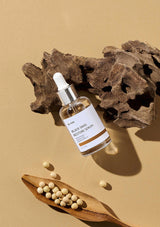 Serum bottle with dropper on a beige background with wooden elements