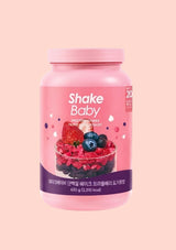 A pink container of Shake Baby protein shake powder with a berry yogurt flavor, shown against a solid pale pink background.