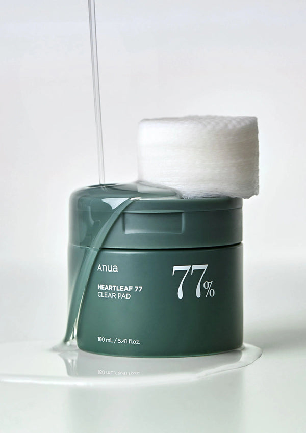 Green jar of '77%' skincare product with cotton pads on a white background
