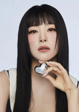 Woman holding a heart-shaped compact mirror against a white background