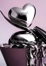 Silver heart-shaped container with 'Olaplex' branding on a pink background