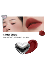 Lipstick with a silver heart-shaped cap, close-up of lips wearing the lipstick, and product name '15 Posy Brick' on a white background.
