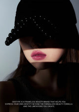 Person wearing a black cap with embellishments, with text about Oddtype beauty brand.