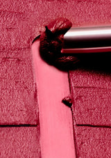 Close-up of a pink door with a silver handle on a red brick wall background