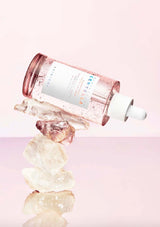 Skincare bottle with crystals on a pink background