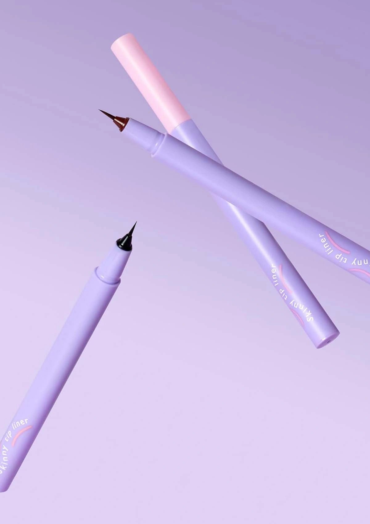 Two purple pens with gold accents on a light purple background