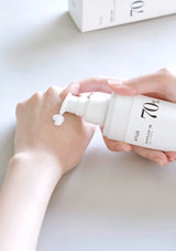 Person holding a white bottle labeled '70' with a pump, on a light surface.