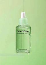 Torriden Balanceful Serum bottle with dropper on a green background