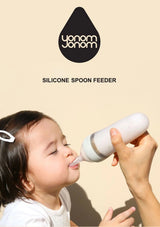 Child using a silicone spoon feeder with 'yonom yonom' branding on a beige background
