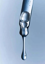 Close-up of a droplet of water on a reflective surface with a gradient background