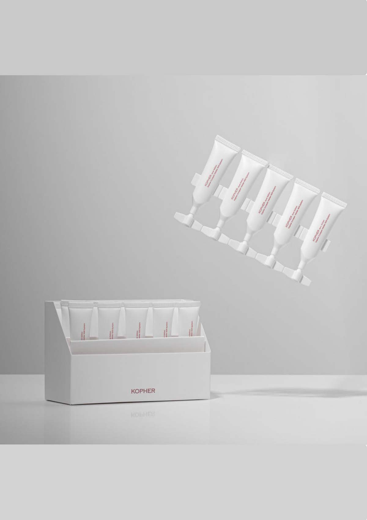White skincare product packaging with multiple tubes on a gray background