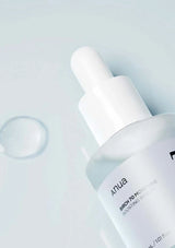 Skincare dropper bottle with 'ANUA' branding on a light gray background