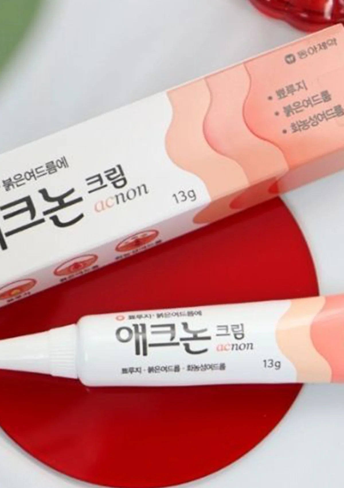 Two tubes of Acne cream with Korean text on a white background
