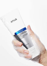 Hand holding a skincare product with 'Anua' branding on a white background