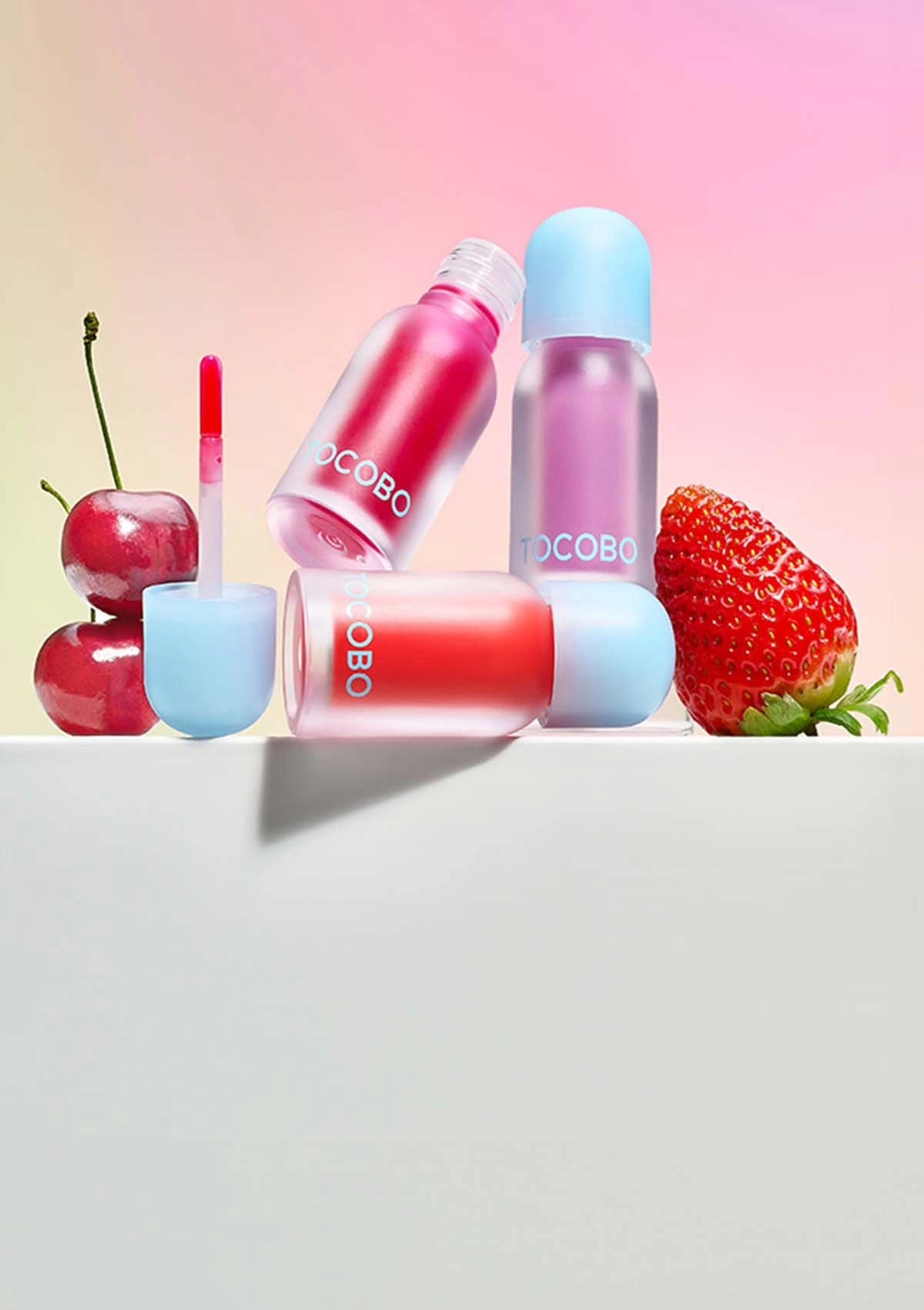 COCOBO lip products with cherries and strawberries on a gradient background
