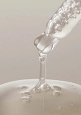 Close-up of a bottle pouring liquid onto a white surface with a blurred background