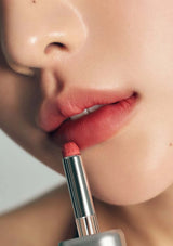 Close-up of a person applying pink lipstick to their lips.
