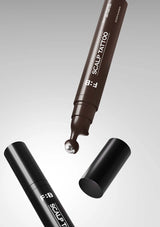 Two scalp tattoo pens with a droplet of ink on a gray background