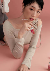 Woman holding a red lipstick with '126 Red Sky' text on a pink background