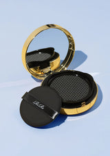 Compact powder with gold lid and black case on a light blue background