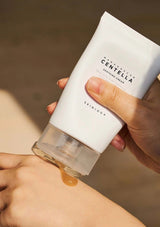 Hand holding a skincare product labeled 'Skinceed' with visible cream on skin.