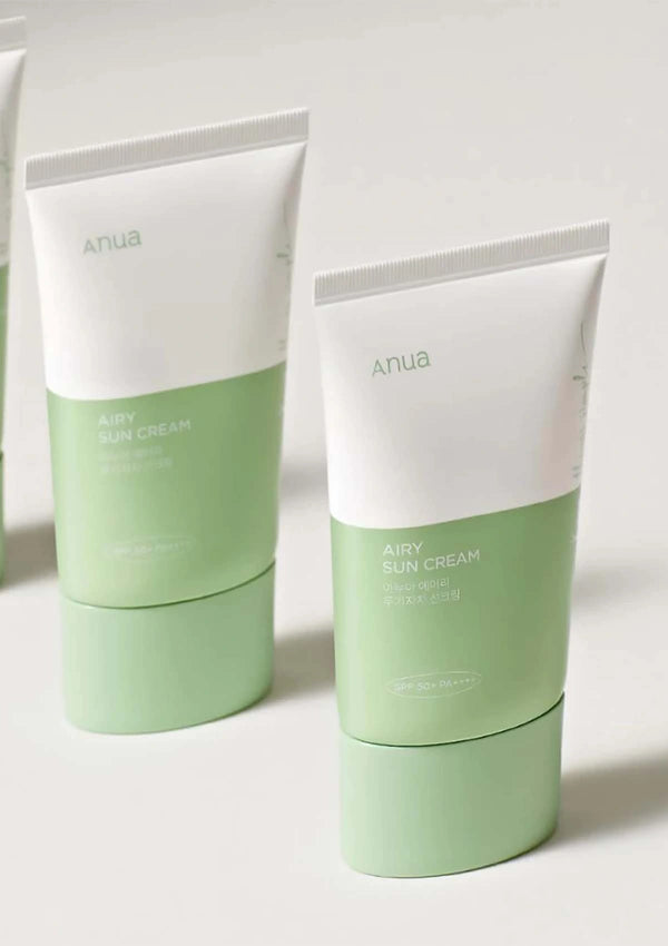 Two green and white tubes of Anua airy sun cream on a light background