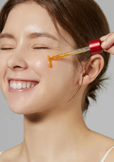 Woman using a skincare tool on her face with a gray background