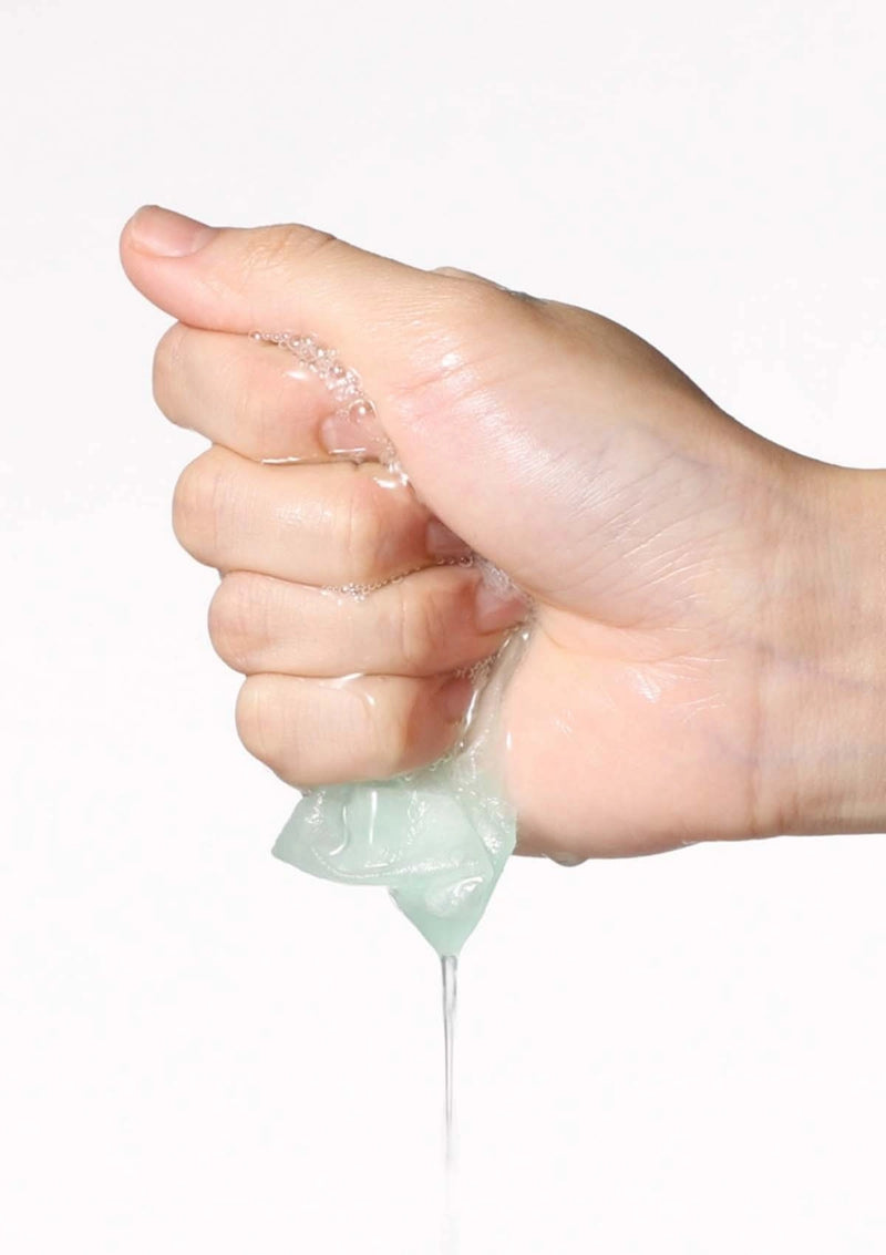 Hand squeezing a small container of clear gel against a white background