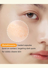 Close-up of a person's face with a highlighted area on the cheek showing small orange dots, with text reading 'Glutathione loaded capsules burst on contact, targeting dark spots for visibly clearer skin'.
