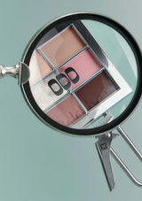 Makeup palette with a magnifying glass on a light green background