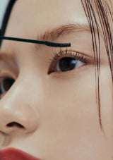 Close-up of a person applying mascara to their eyelashes.