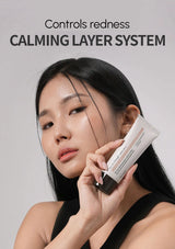 Woman holding a skincare product with 'Controls redness CALMING LAYER SYSTEM' text on a gray background