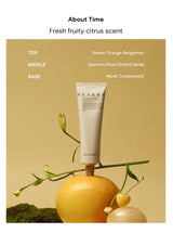 Tube of 'Nearby' perfume with a grapefruit and flower arrangement on a beige background