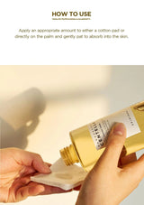 Gold bottle being used to apply a product to a cotton pad with text on how to use it.
