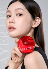 Woman holding a red compact with 'VELVET VELVET' branding against a gray background