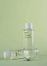 Two bottles of REFLECTION Lotus Toner on a green background