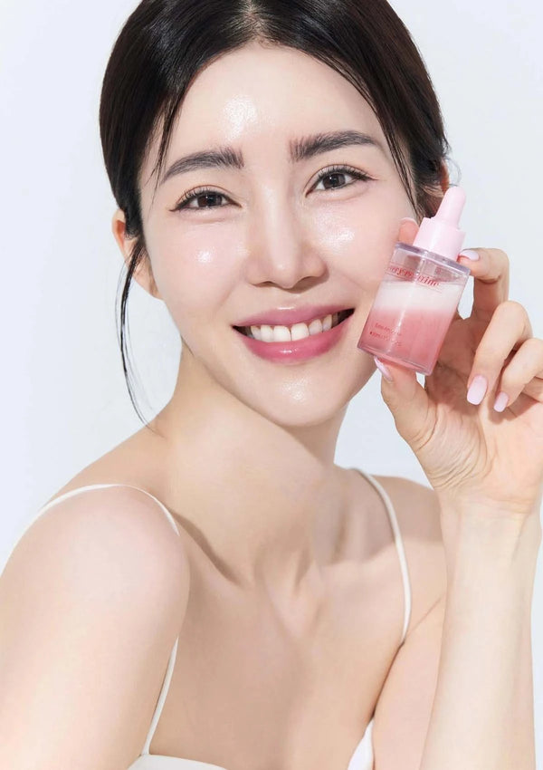 Woman holding a pink skincare product against a white background