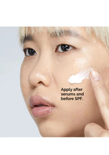 Person applying cream to their face with text on a light gray background