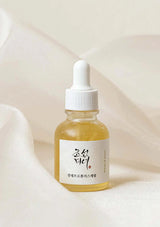 Bottle of skincare serum with a white cap on a soft beige background