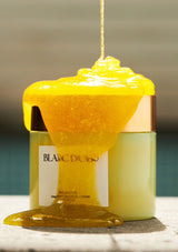 Yellow substance being poured from a container labeled 'Blanc Dubu' on a blurred background