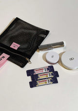 Black mesh pouch, compact powder, and lip balm on a white surface
