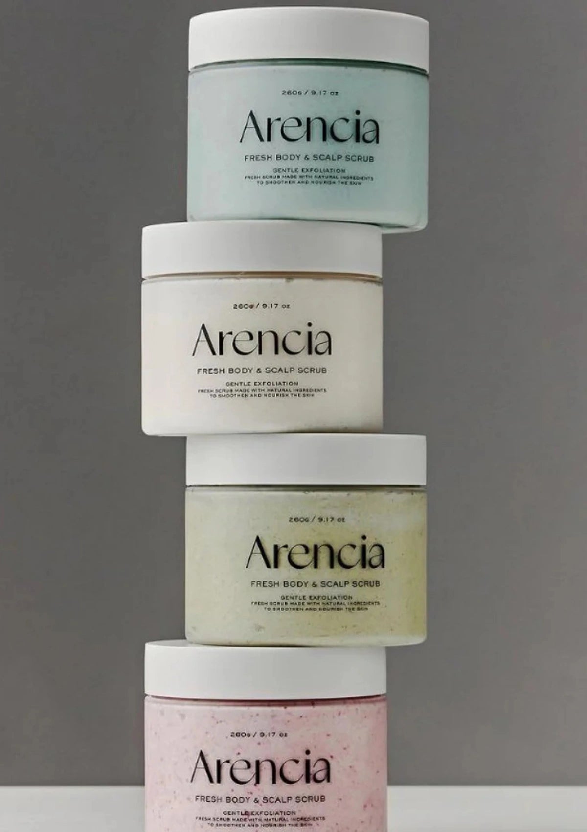Stack of Arencia fresh body & scalp scrubs on a gray background