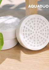 White shower head with a textured surface on a wooden background, featuring the brand 'Aquaduo'.