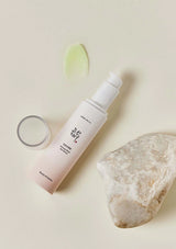 Skincare bottle with a rock and green leaf on a beige background