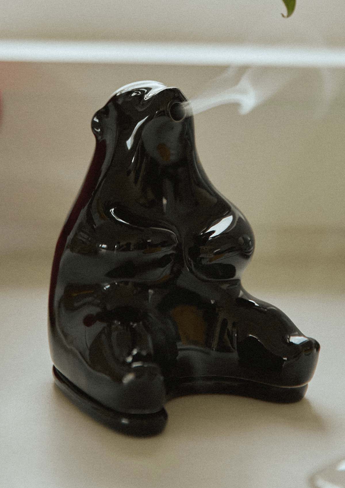 A black ceramic incense chamber designed to resemble a honey badger, with smoke rising from it.