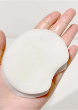White makeup sponge held in a hand against a light background