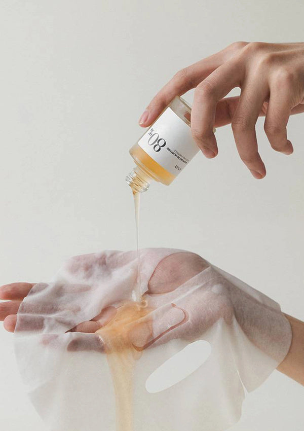 Person pouring a liquid from a bottle labeled 'W8' onto their hand against a light background