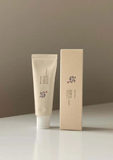 Beige tube and box with brand logo on a neutral background